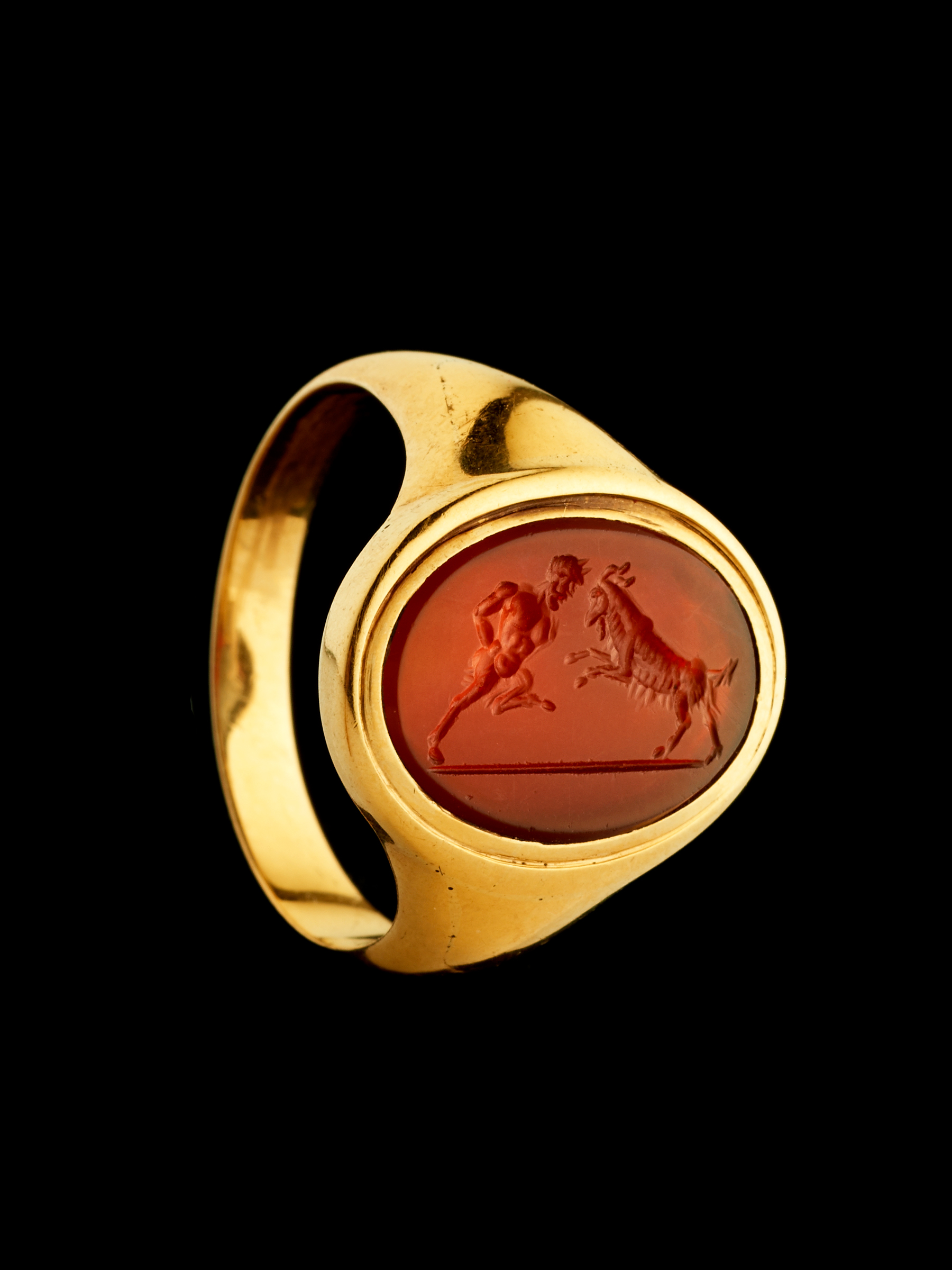 A 18k signet ring set with a Grand Tour carnelian intaglio. Pan fighting a goat. 